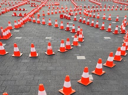 Aerial view of traffic cones arranged on a paved surface, forming a complex pattern.